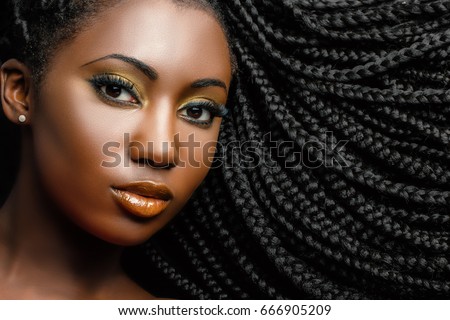 Extreme close up beauty portrait of young african woman showing long braided hair next to face. Royalty-Free Stock Photo #666905209