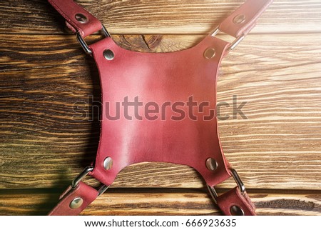Central part pink camera harness, camera strap harness, leather camera strap on brown wooden background. Glare. Photo.