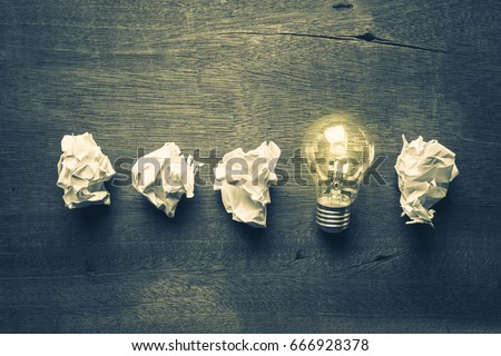 Light bulb glowing in a row of crumpled ball paper, learning from mistake Royalty-Free Stock Photo #666928378