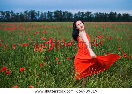 the long hair brunette girl in the red dress dancing on field of poppies 