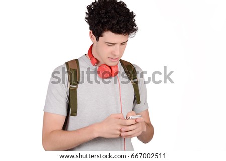 Portrait of young latin man with backpack and using his smartphone. Isolated white background.