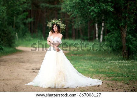 Beautiful bride in a white dress with a wreath of flowers
