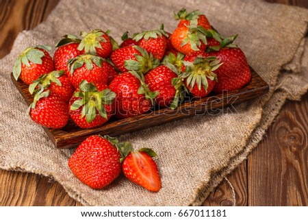 Picture of fresh ripe strawberries on wooden plate, linen fabric closeup