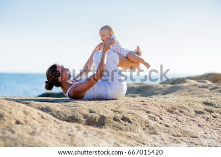 A mother and a son are doing yoga exercises at the seashore of Mediterranean sea