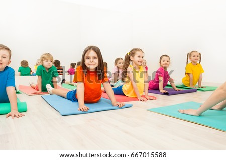 Kids stretching backs on yoga mats in sports club Royalty-Free Stock Photo #667015588