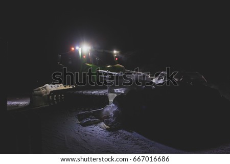 Snowcat bulldozer with multicolored light drives on the slopes and maintenance on the mountains ski resort
