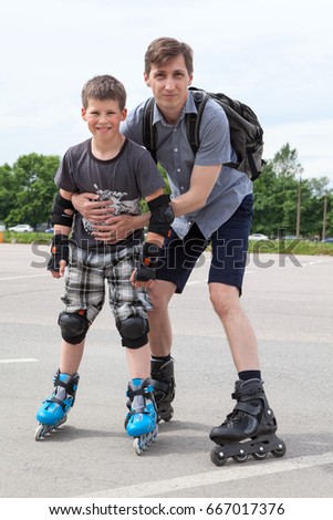 Portrait of European father and son rollerblading on roller-skates in urban park