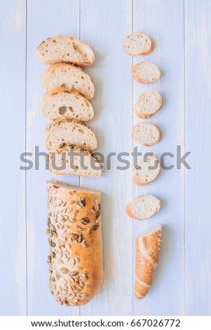 Fresh sliced mixed seed baguette on the wooden table, top view.