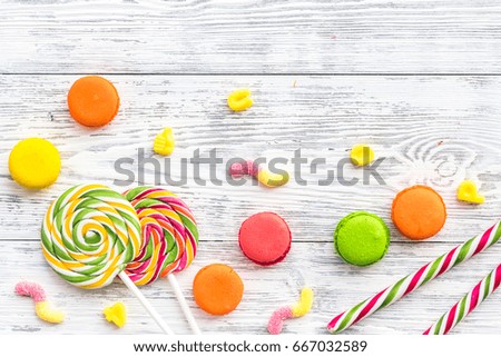 Sweets for birthday including lollipop and macarons on wooden desk top view copyspace