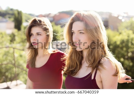 Portrait of two pretty girls on the roof on setting sun, having fun
