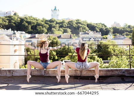 Portrait of two ballerinas on the roof on setting sun, dancing and  training