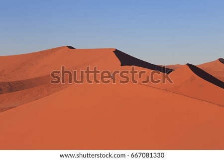 Man  on sand dune in desert during sunrise.  Sossusvlei, Namib Naukluft National Park, Namibia