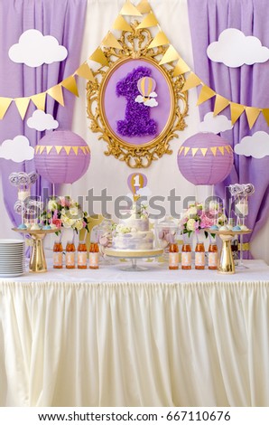 Interior decoration kids child birthday sweet candy bar one year in ultra violet color trend year purple colors. Candy, macaroon, tiered cake, and juices, air balloons. Anniversary dating celebration. Royalty-Free Stock Photo #667110676