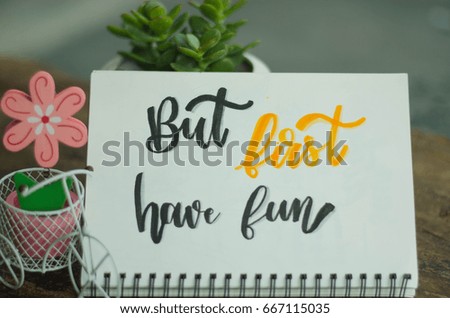 Calligraphy handwriting inspirational quote BUT FIRST HAVE FUN on white notebook