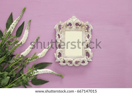 top view image of spring beautiful white flowers and blank victorian photo frame on wooden background. Ready to put photography