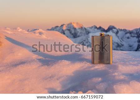 Hip flask in the mountains at sunset.
