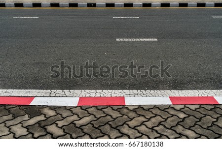 Asphalt road with red and black and white traffic sign at sidewalk curb