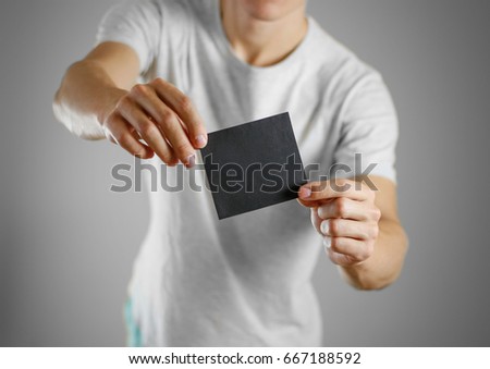 A man in a gray t-shirt holding blank clear black of the sheet. Closeup. Isolated