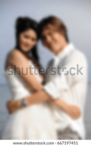 Blur style picture of wedding concept, groom in casual clothes hug bride in short wedding dress at the sea.