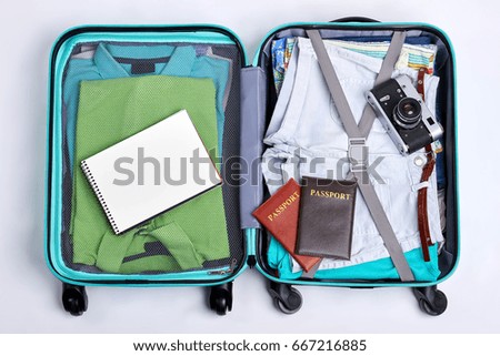 Open suitcase with accessories. Passports, camera, note, clothes. Concept of vacation.