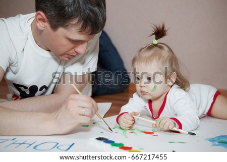Happy father and daughter paint lying on the floor at home. The view from the top.