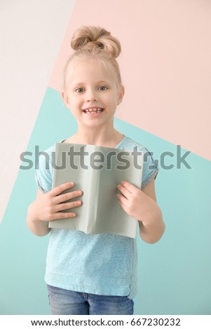Cute funny girl with book on color background
