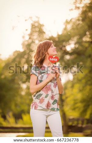 Girl posing with heart - shaped love sign.