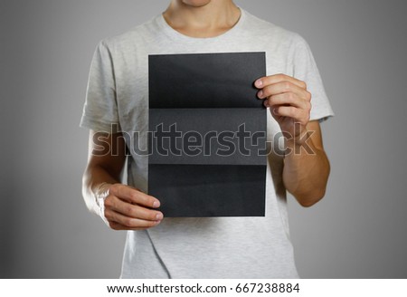 A man in a gray t-shirt holding blank clear black of the sheet. Closeup. Isolated.