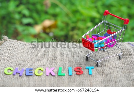 Shopping trolley with wording CHECKLIST concept. Presented on a rag with the nature background.