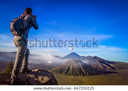 Trekker taking photo of Gunung Bromo volcano in Java, Indonesia
