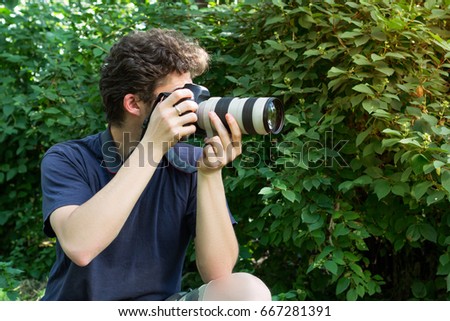 A portrait photographer who takes the photo. In background of green bushes. Photo.