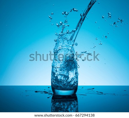 Creative splashing water in the glass on blue background. 