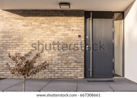 Minimalist clean red brick home exterior with black front door