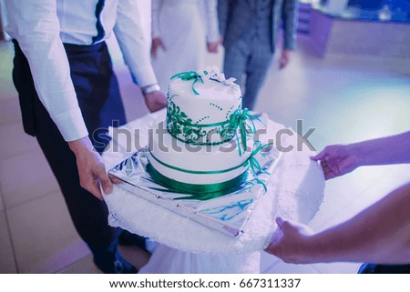 The close-up view of the white wedding cake decorated with green ribbons.