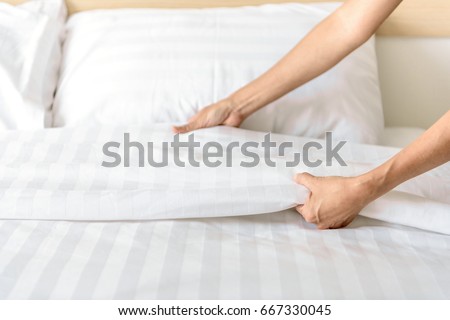 Hand set up white bed sheet in room Royalty-Free Stock Photo #667330045