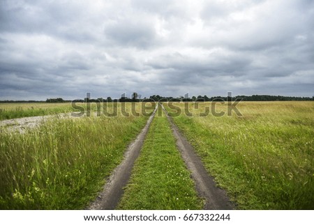 Dirty road landscape, cloudy day, summer time in Poland.