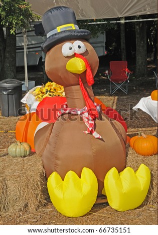 Huge inflatable turkey wearing a top hat with pumpkins.