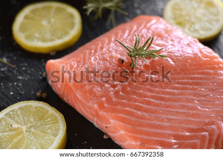 Raw salmon fillets served with lemon, pepper and rosemary leaves 