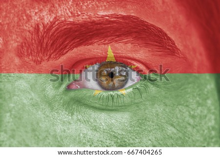 Human face and eye painted with flag of Burkina Faso