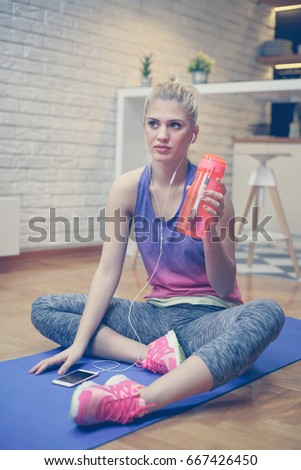 Woman in sportswear relaxing after a workout. Beautiful blonde woman in sportswear and earphone filing tired after workout.