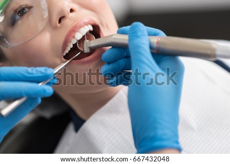 Dentist curing oral cavity of cheerful woman Royalty-Free Stock Photo #667432048