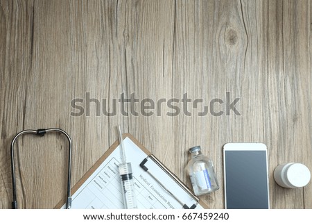 top view of medical examination report,cellphone,and medical equipments on wooden desk