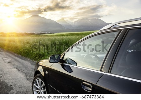 Car is driving on the country road, on the background of rocky mountains.