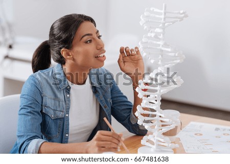 Smart young woman looking at the DNA model