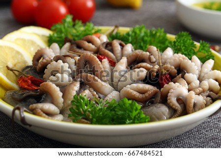 Octopus salad in ceramic dish on kitchen table background