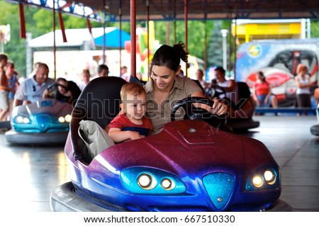 Mother and 2 years old baby pay drive dodgem together in the theme-park. Royalty-Free Stock Photo #667510330