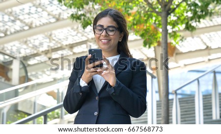 Young beautiful business woman (student) in a suit, smiling, happy, going down stairs, steps, talking on the phone, writing a message. Concept: new business, communication, Arab, banker, glasses, call