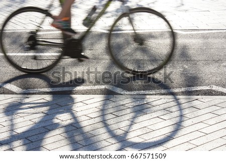 Blurry cyclist silhouette and shadow on a  bike lane 