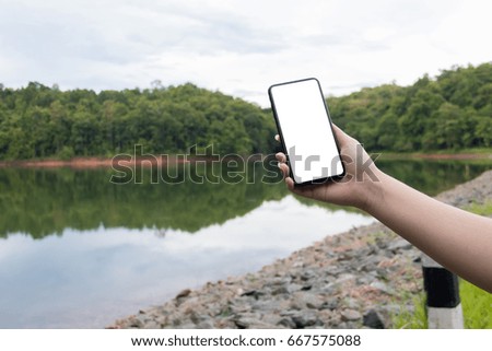 Mock up woman hold cellphone on riverside with green nature background. business concept