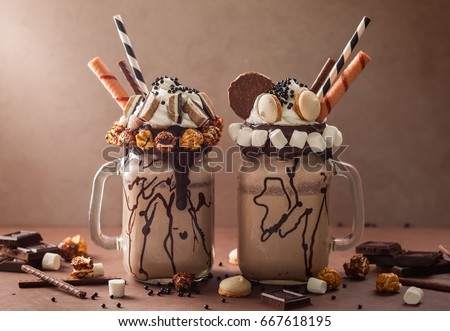 Chocolate  milkshake with ice cream and with whipped cream, marshmallow, sweet popcorn, cookies, waffles, served in glass mason jar. "Freak or crazy" sweet shake. Royalty-Free Stock Photo #667618195